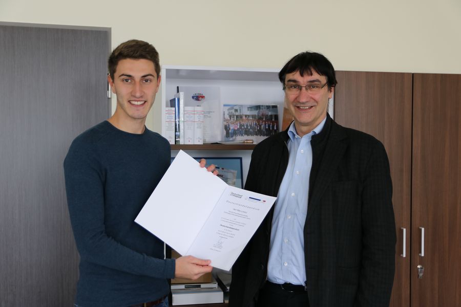 Foto: Hr. Prof. Kassel überreicht einem Studierende eine Urkunde zum Deutschlandstipendium.
