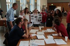Foto: Eine Gruppe Schülerinnen präsentiert am Jury Tisch ihr Plakat zum Solar Modellauto Projekt.