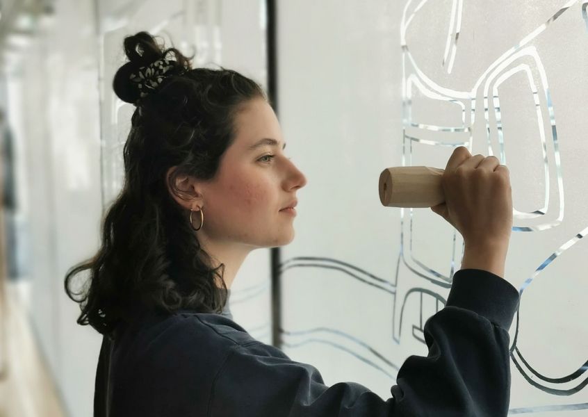 junge Frau bei der Erstellung eines Kunstwerks an einer Glasfassade