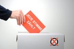 Foto: Ein Hand wirft einen Stimmzettel in eine Wahlurne.