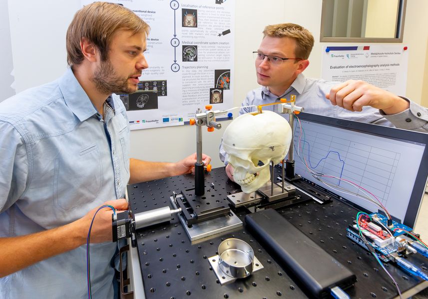 Foto: Zwei Wissenschaftler am Versuchsaufbau eines intelligenten Hirnspatels.