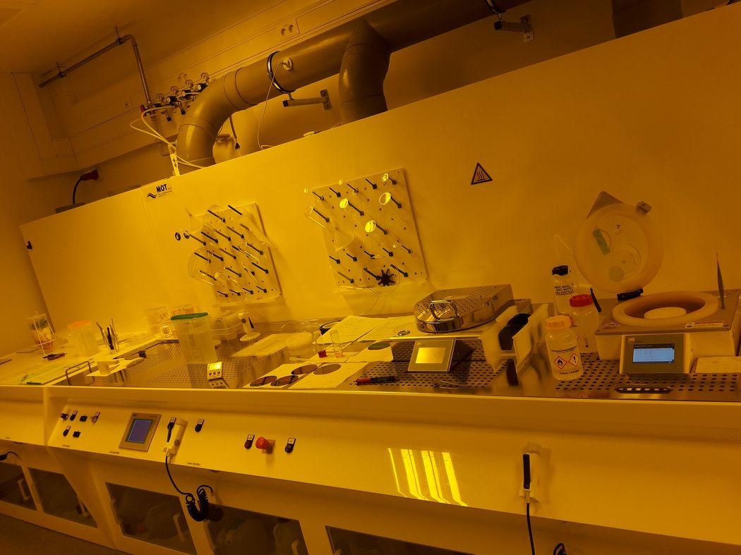 Foto: Laborarbeitsplätze mit Geräten der physikalischen Technik im Gelblichtbereich.