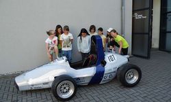 Foto: Mädchen stehen um einen Formula Student Wagen beim WHZ Racing Team.