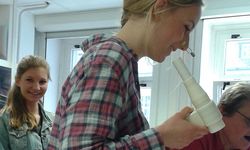Foto: Eine Schülerin mit einer Nasenklammer tätigt unter Anleitung einen Versuch im Biomedizinlabor.