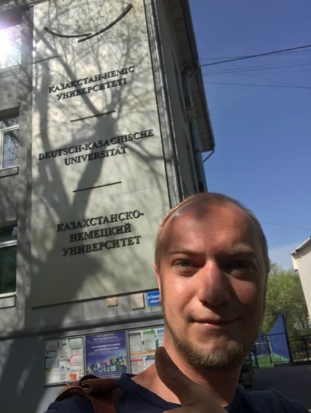 Foto: EIn Hr. Mario vor der Ecke eines Gebäude stehend. Im Hintergrund ein Schild der Deutsch-Kasachischen Universität.