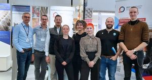 Gruppenbild von acht Standbetreuern und ehemaligen Absolventen am Messestand