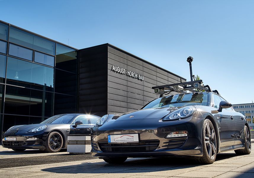 Foto: Ein Porsche steht vor dem Gebäude der Fakultät Kfz-Technik. Auf dem Fahrzeug befinden sich diverse Kameras und Messapparaturen. 