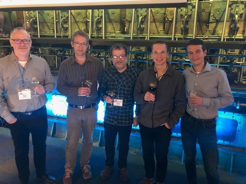 Foto: Gruppenbild mit fünf Herren. Jeder hält von Ihnen ein Weinglas in der Hand.