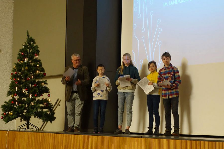 Auf der Bühne der Aula Scheffelberg stehen zur Preisverleihung 4 Schuler und ein Lehrer mit Urkunden in der Hand. Daneben steht ein Weihnachtsbaum. (Foto: WHZ/M. Schwedler)