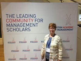 Foto: Frau Prof. Walter steht vor einem Plakat mit der Aufschrift. The Leading Community for Management Scholars.