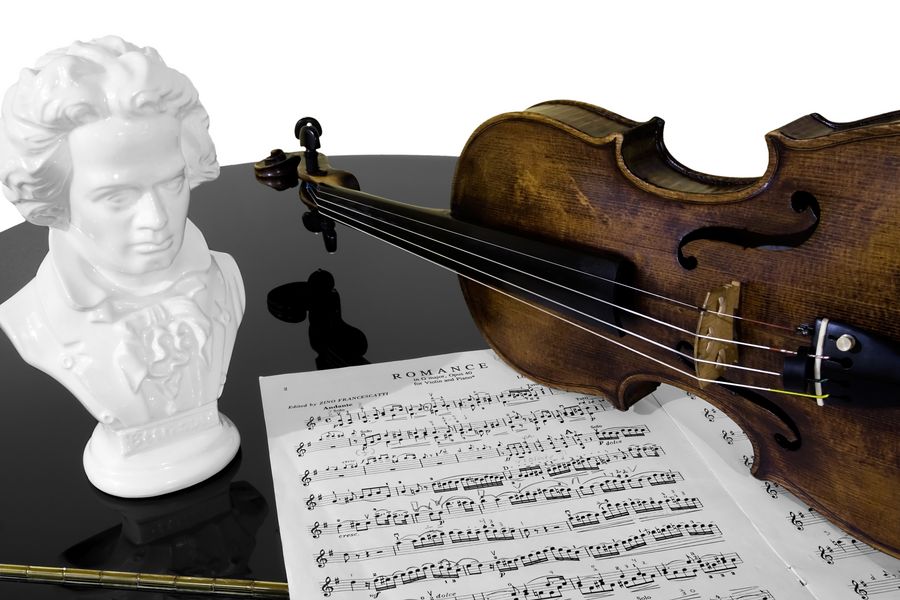 Foto: Eine Geige, eine Büste und ein Notenblatt auf einem Tisch.