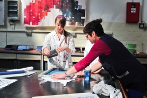 Foto: Zwei Studierende tätigen unter Anleitung einen Textildruck. Textiles "Begreifen" im Technikum des ITL. Bildquelle: Susanne Baumung