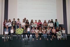 Foto: Schülerinnen sitzen und stehen in der Aula Scheffelberg auf der Bühne. Sie halten dabei ihre selbst gebastelten Themenplakate hoch.