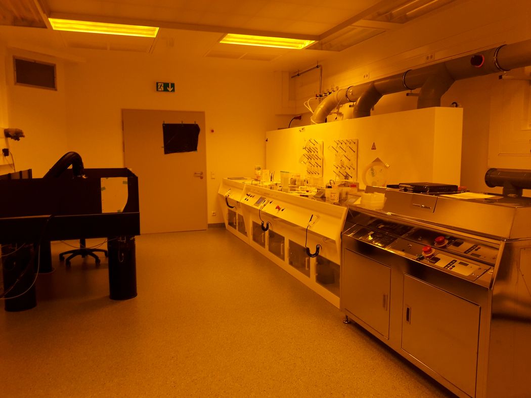 Foto: Laborarbeitsplätze mit Geräten der physikalischen Technik im Gelblichtbereich.