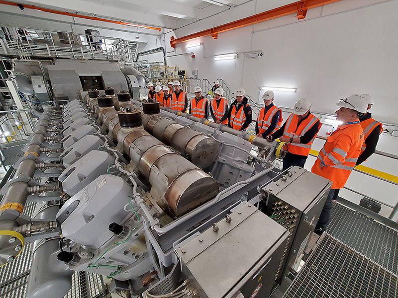 Eine Gruppe Studierende steht vor dem riesigen Motor in Kraftwerk (Rechte WHZ: Prof. Walther)