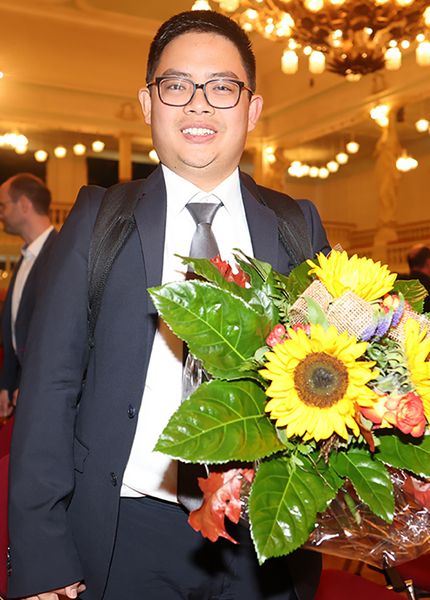 Strahlender Preisträger Dennis Buddy Saputra aus Indonesien mit Blumenstrauß