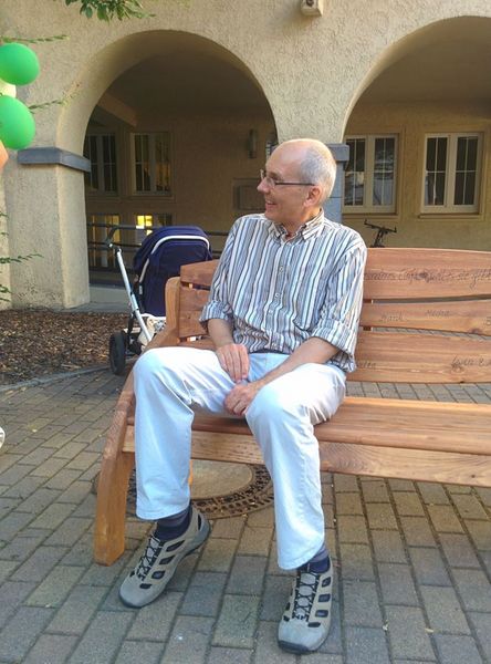 Foto: Hr. Prof. Beier sitzt auf einer Holzbank im Bibliotheksinnenhof.