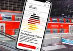 Handy mit Deutschlandticket - im Hintwergrund ein stehender Regionalzug