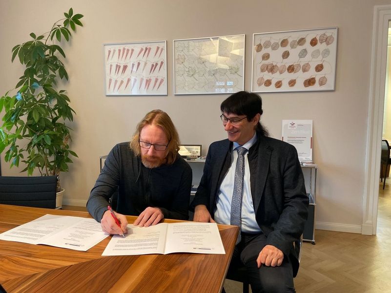 Foto: Herr Dahle und Prof. Dr. Stephan Kassel, Rektor der WHZ, sitzen an einem Tisch und unterzeichneten ein gemeinsames Memorandum of Understanding.