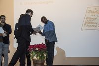 Foto: Drei Absolventen erhalten eine Gratulation und bekommen Urkunden überreicht.