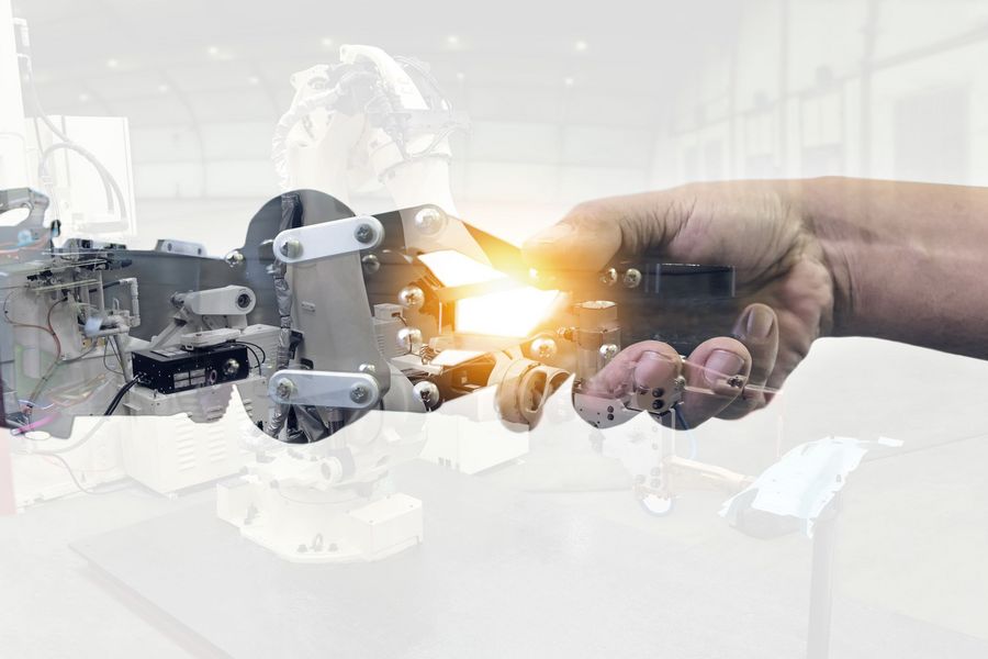 Foto: Ein Robotergreifarm und eine menschliche Hand versuchen einen Händedruck darzustellen.