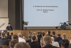 Foto: Absolventen sitzen in der Aula Scheffelberg. Am Rednerpult Prof. Dr. Stephan Kassel.