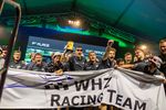 Studierende feiern hinter einenm Banner mit der Aufschrift WHZ Racing Team