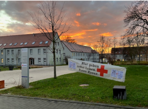 Das Bild zeigt den Campus Scheffelberg beim Sonnenuntergang mit einem Werbebanner zur Blutspendeaktion.