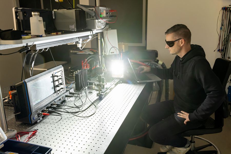 Ein Forscher arbeitet mit einer Schutzbrille in einem Labor, vor ihm eine Lichtquelle