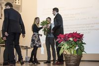 Foto: Zwei Absolventen bekommen Blumen überreicht.