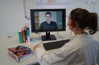 Foto: Eine Studierende führt an einem Monitor ein Videogespräch mit einem Studierenden.