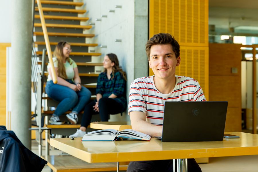 Ein Student sitz vor einem laptop in der Hochschulbibliothek