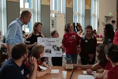 Foto: Eine Gruppe Schülerinnen präsentiert ihr Präsentationsplakat und Solar Modellauto am Jury Tisch.