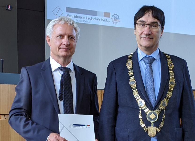 Dr. Bernhardt Karich hält die Ernennungurkunde in der Hand, neben ihm WHZ-Rektor Prof. Stephan Kassel mit Amtskette. 