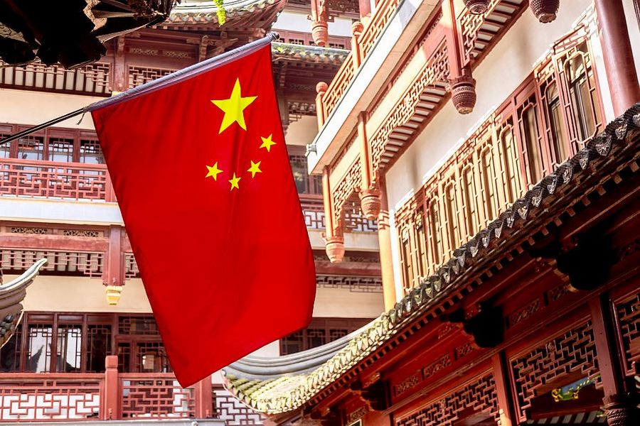Foto: Auf der linken Seite ist groß die chinesische Flagge, im Hintergrund ein traditionelles chinesisches Gebäude.