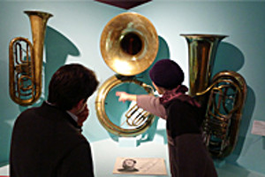 Foto: Berlin besuch. 2 Interessierte betrachten ausgestellte Blasinstrumente.