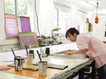 Foto: Eine Studierende in einem Atelier beim Siebdruck.