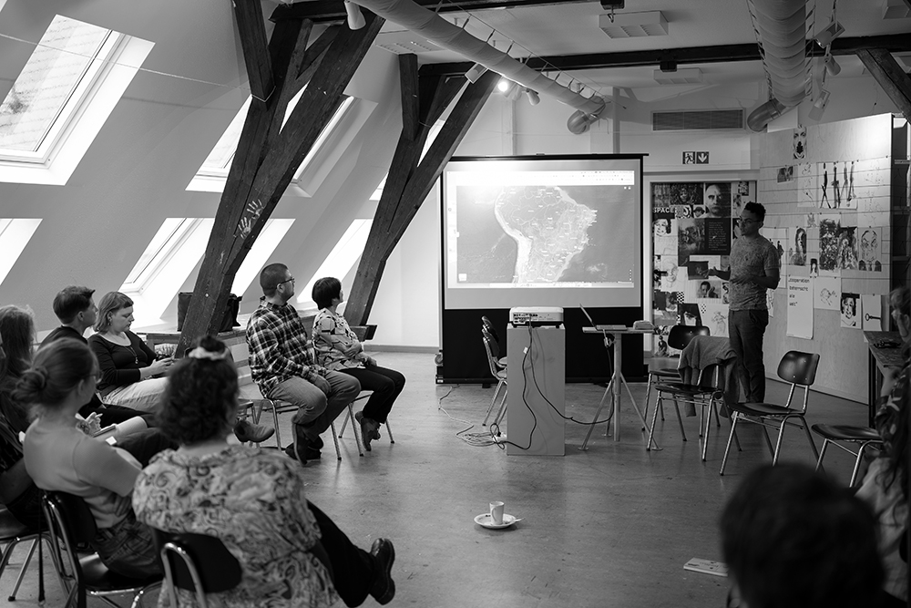 Foto: Symposium "ost in space", Teilnehmende hören einem Redner zu, Schwarz-Weiß-Fotografie (Fotoquelle: Lars Preisser)