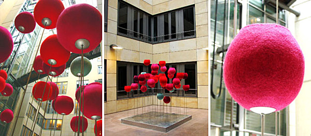 Fotoreihe: Aus roten Stoff geformte Kugeln stehen in einem Innenhof auf Stangen. Elisabeth Christine Matschke Tulipa – Textile Installation für den Innenhof eines Bürogebäudes.