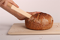 Foto: Projekt "Brotbacken", ein Brot wird mit hölzernem Brotmesser geschnitten