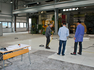 Foto: Drei Mitarbeiter vermessen den Standort der neuen Werkzeugmaschine in der Laborhalle.