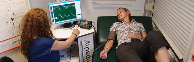 Bannerfoto: Eine Studierende liegt auf einem Untersuchungsbett mit einem Blutdruckmessgerät. Eine andere Studierende wertet die Daten auf einem Monitor aus. Medizin- und Gesundheitstechnologie (Master)