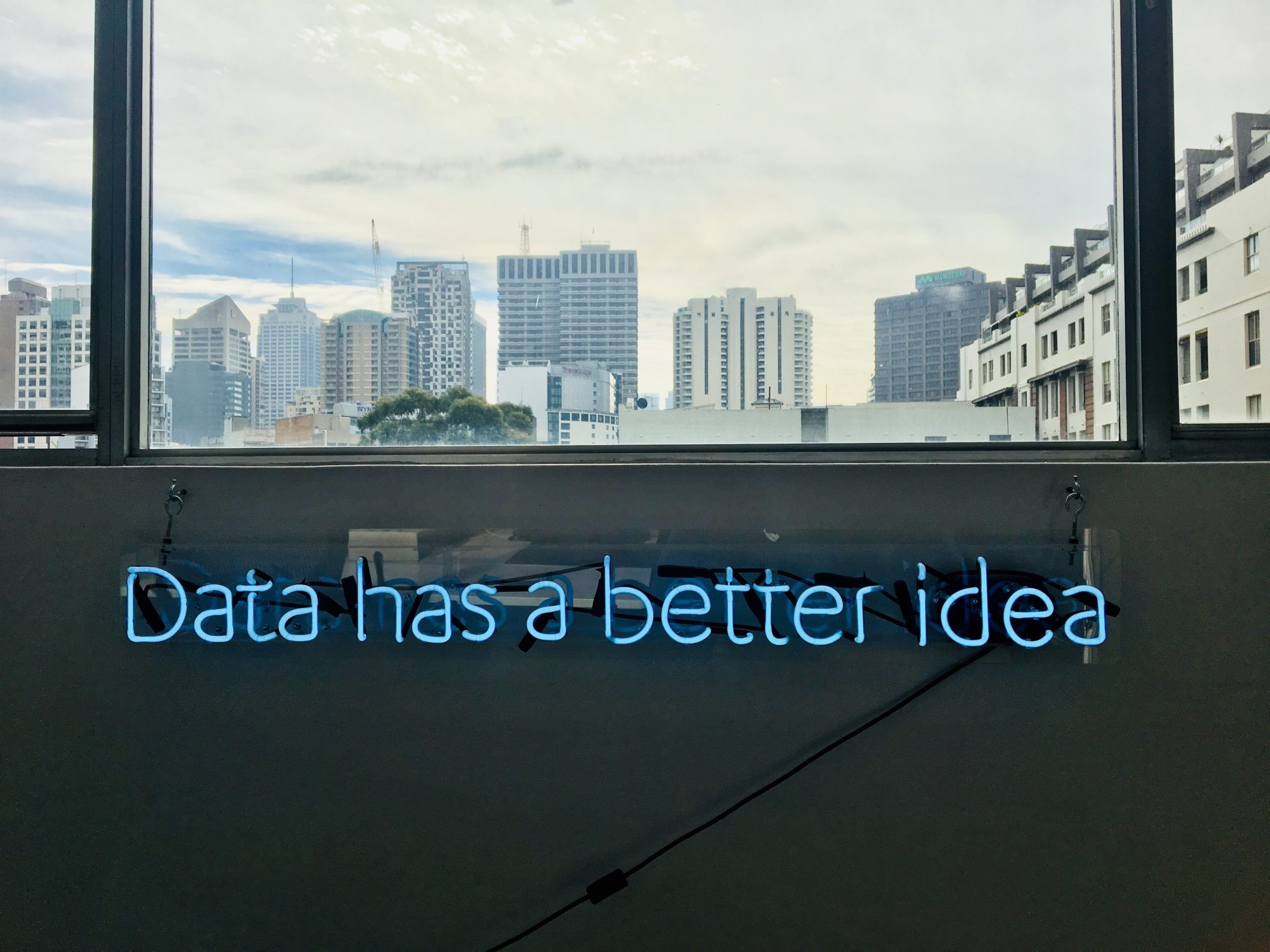 Foto: Blick durch ein Fenster auf die skyline einer Stadt. Text im Bild. Data has a better idea.
