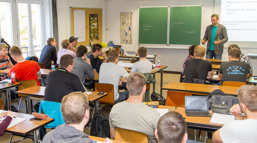 Foto: Studierende sitzen in einem Klassenzimmer und hören einer Vorlesung zu.