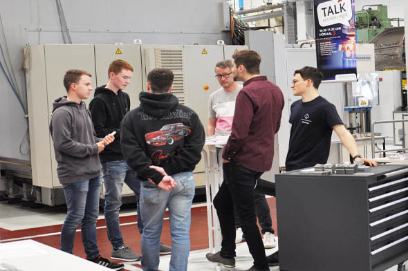 Studenten unterhalten sich in Maschinenlabor mit interessierten Schülern