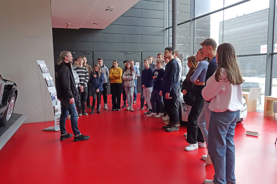 Die Schülerinnen und Schüler stehen im Foyer des August-Horch-Bau vor dem Audi-Schnittmodell, gegenüber erklärt der Laboringenieur Herr Bau(Foto: WHZ/M. Schwedler)