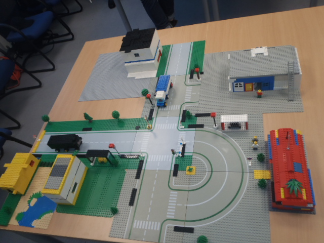 Foto: Eine Lego Konstruktion steht auf einem Tisch. Mit Unterplatten, Gebäuden und Fahrzeugen darauf.