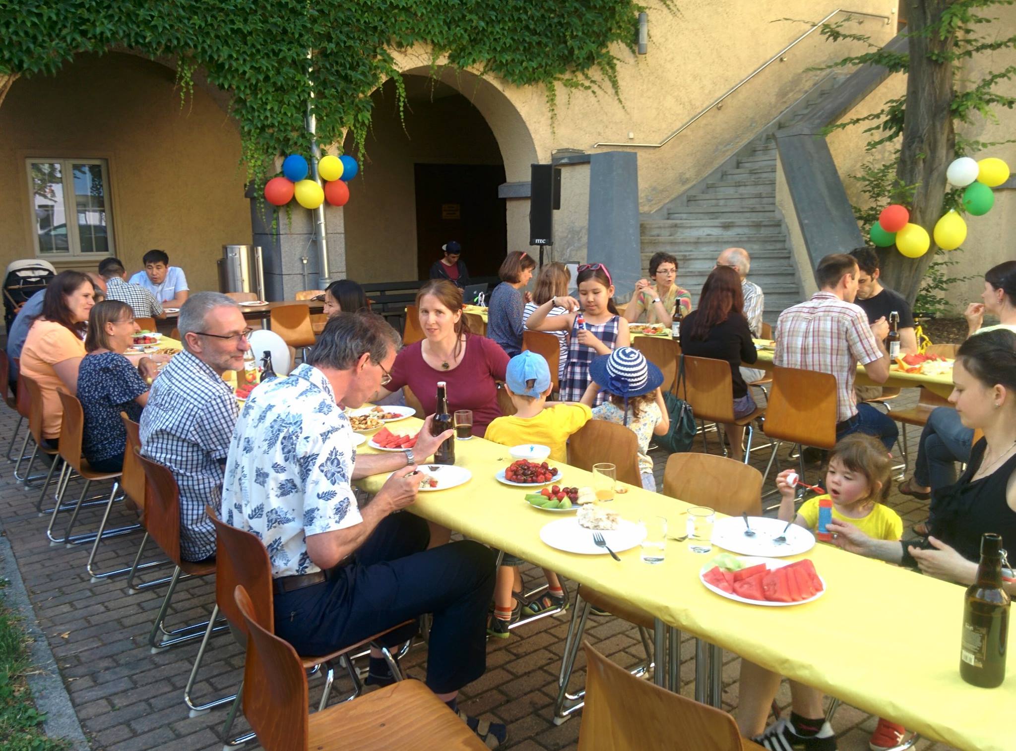 Foto: Tischreihen im Hauptbibliotheks Innenhof. Gäste sitzen gemeinsam bei essen und trinken. Verabschiedungsfeier von Hr. Prof. Beier.