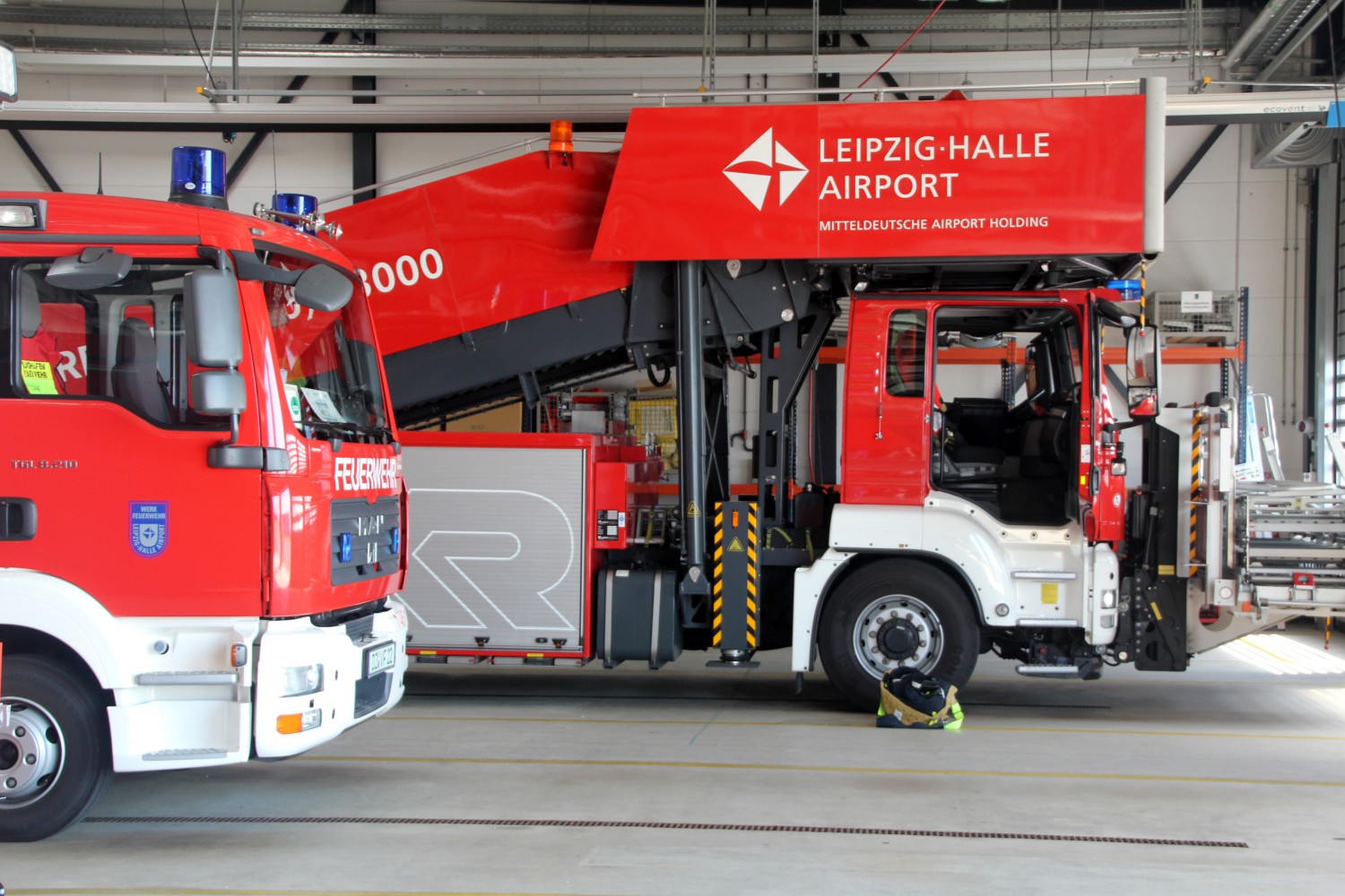 Foto: Seitliche Ansicht des vorderen Bereiches zweier Feuerwehrfahrzeuge in einer Halle des Flughafen Leipzig.