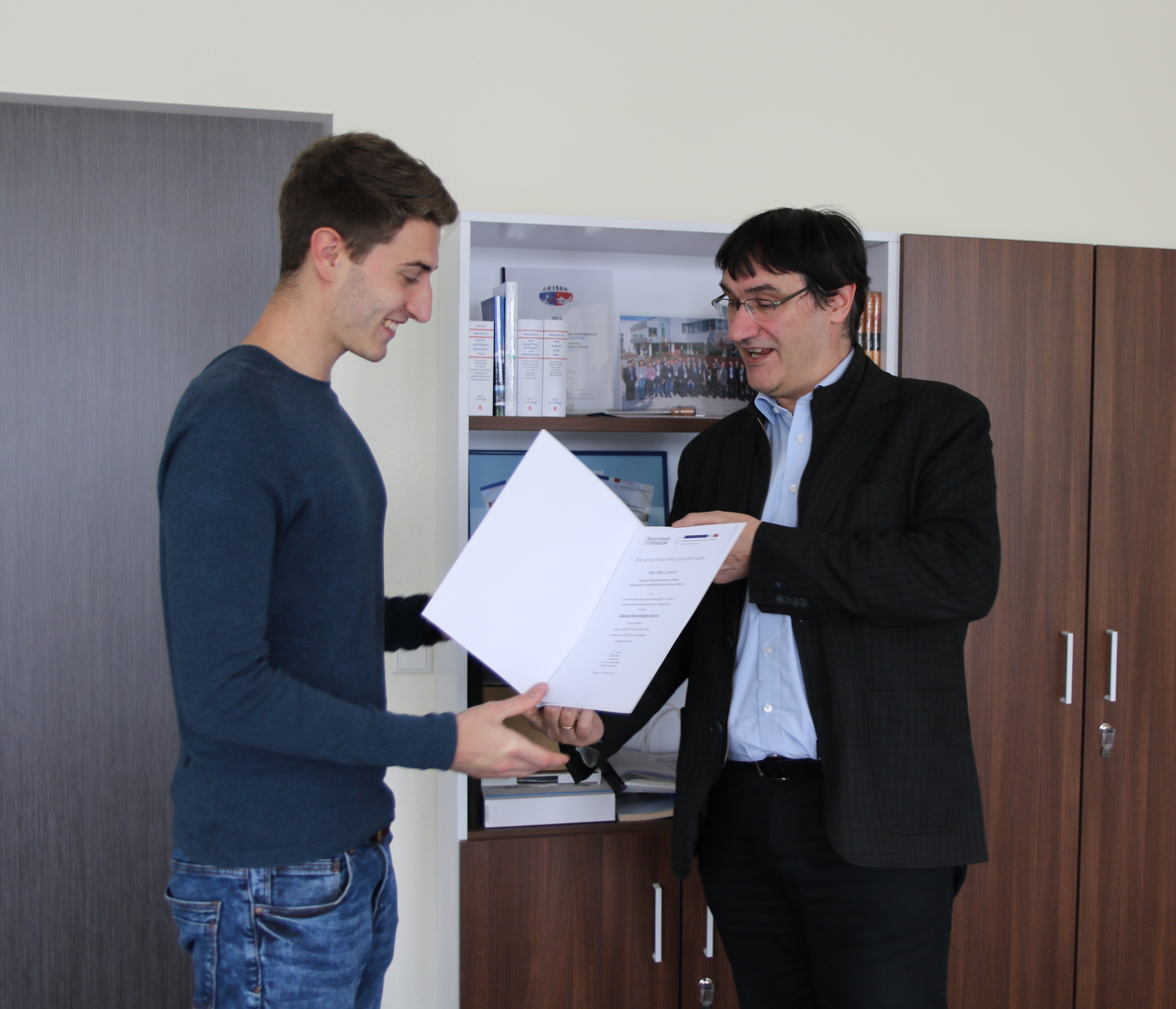 Foto: Hr. Prof. Kassel überreicht einem Studierende eine Urkunde zum Deutschlandstipendium.